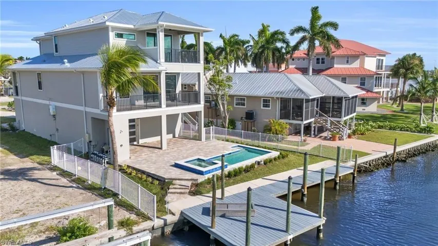 Rear view of house featuring a balcony, a water view, a patio, and a fenced in pool