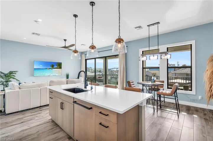 Kitchen featuring decorative light fixtures, light hardwood / wood-style floors, sink, an island with sink, and ceiling fan