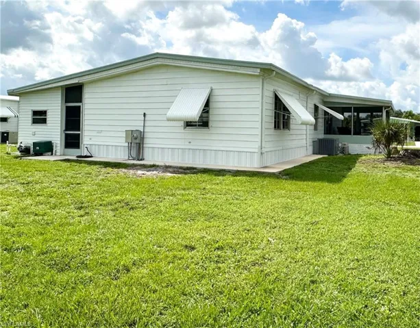 View of side of property with cooling unit and a lawn