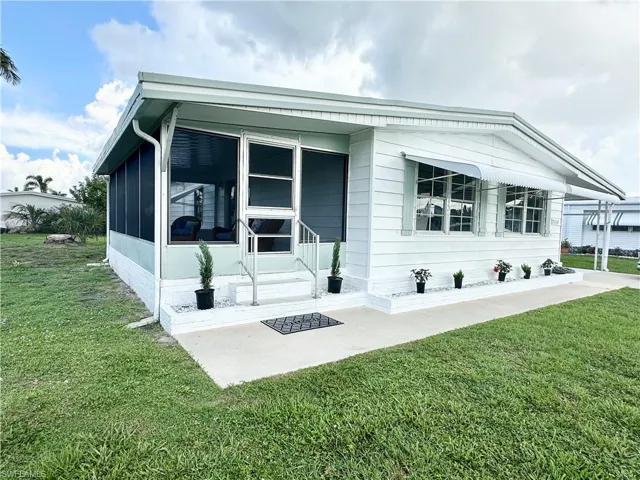 Back of property with a sunroom and a lawn