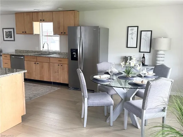 Kitchen with stainless steel appliances, light stone countertops, sink, and light wood-type flooring