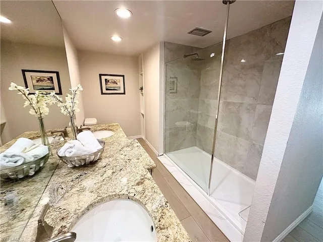 Bathroom with walk in shower, toilet, and dual bowl vanity