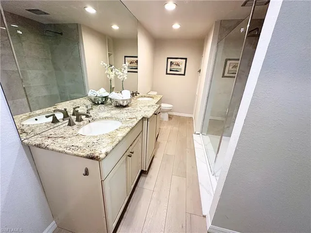 Bathroom featuring vanity, toilet, a tile shower, and hardwood / wood-style flooring