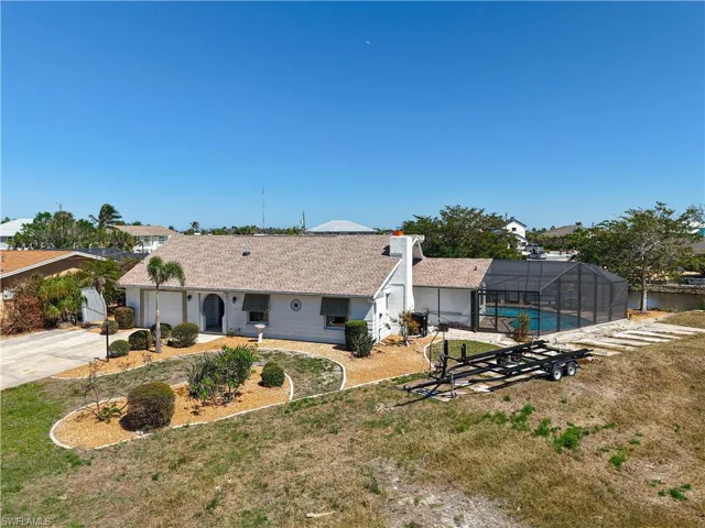 View of front of house featuring glass enclosure, a front lawn, concrete driveway, and an outdoor pool