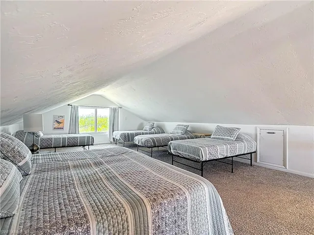 Bedroom with a textured ceiling, vaulted ceiling, and carpet floors