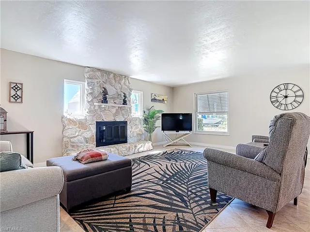 Living room with a stone fireplace, plenty of natural light, a textured ceiling, and tile patterned floors