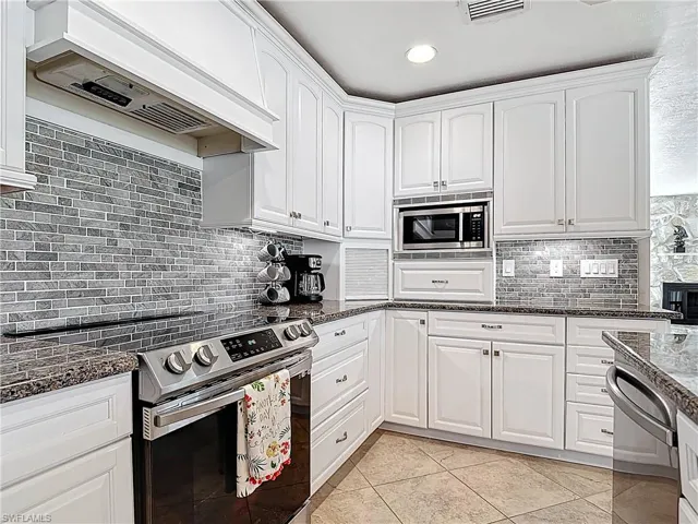 Kitchen with stainless steel appliances, white cabinets, premium range hood, and recessed lighting