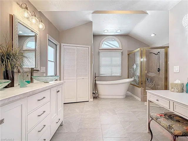 Full bathroom with vaulted ceiling, a stall shower, a freestanding tub, and vanity