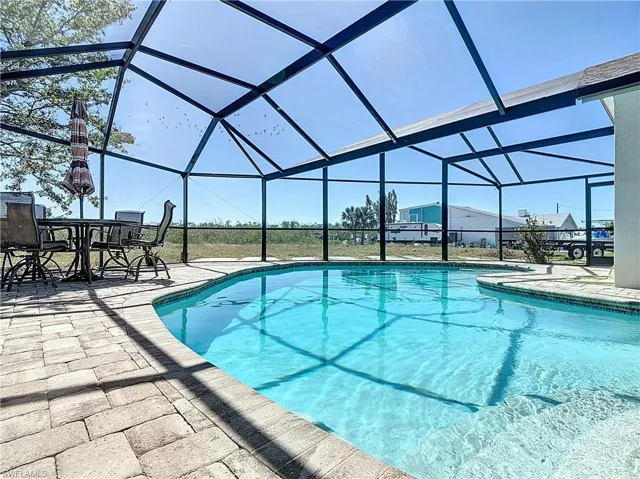 Outdoor pool featuring a sunroom, glass enclosure, and a patio area