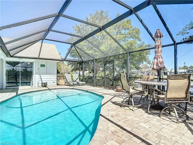 Swimming pool featuring glass enclosure, a patio area, a sunroom, and outdoor dining space