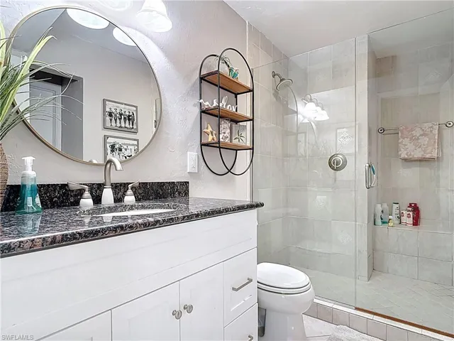 Bathroom featuring vanity, a textured wall, and a shower stall