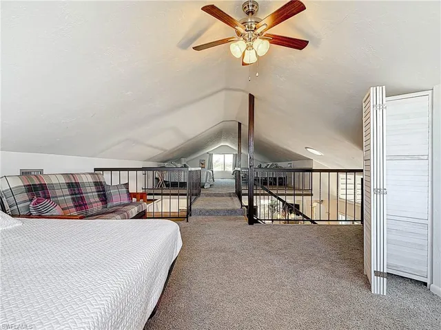 Carpeted bedroom with a textured ceiling and vaulted ceiling