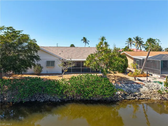 Rear view of house with a sunroom, a lanai, a water view, and a shingled roof