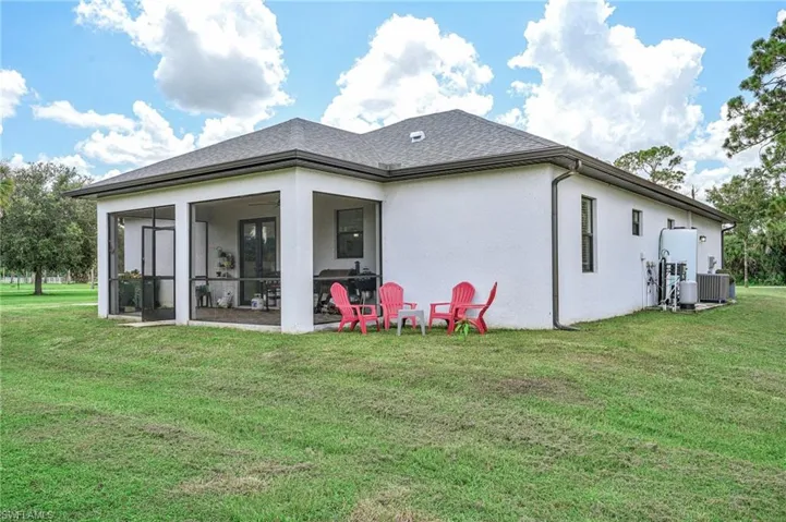 Rear view of property with a sunroom, central AC unit, and a lawn
