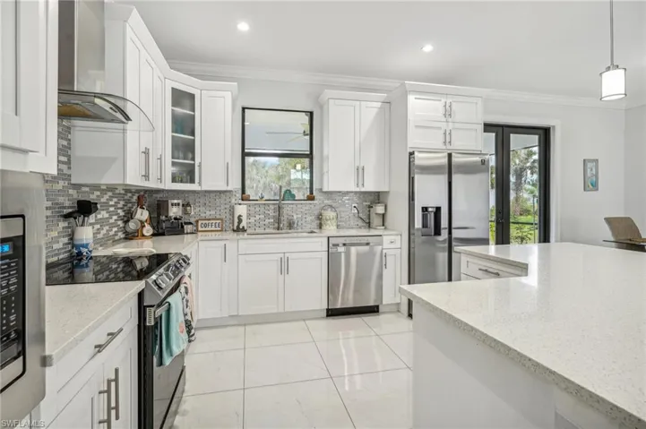 Kitchen with wall chimney range hood, sink, backsplash, and stainless steel appliances
