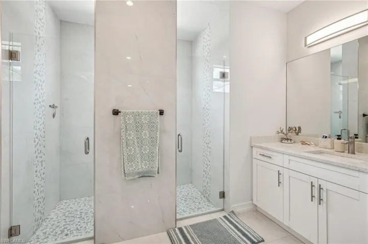 Bathroom featuring tile patterned floors, a shower with shower door, and vanity