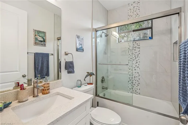 Full bathroom with toilet, bath / shower combo with glass door, and vanity