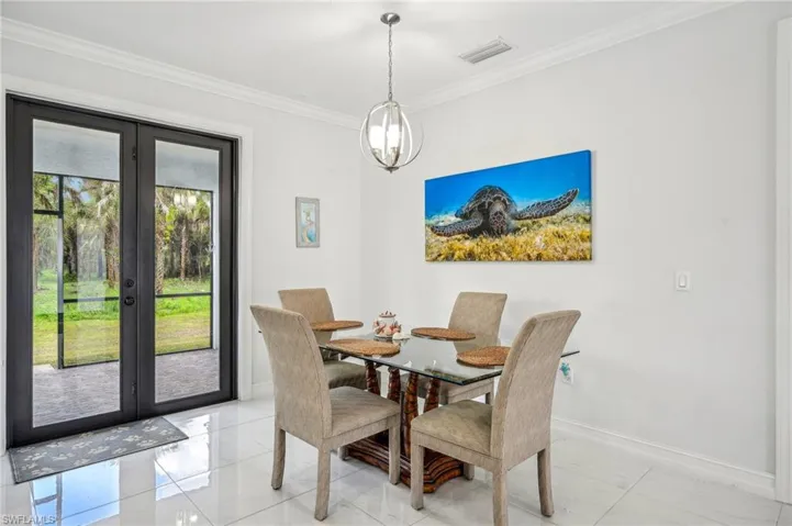 Tiled dining space featuring a notable chandelier, french doors, crown molding, and a healthy amount of sunlight