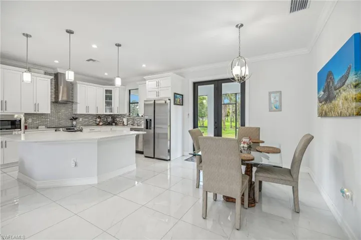 Tiled dining area featuring crown molding, a chandelier, and french doors