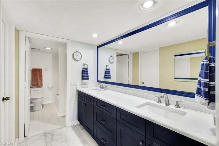 Dual Raised Wood Cabinetry in Navy Blue, Quartz, Dual Sinks and Storage, Walk In Closet