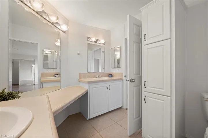 Full bathroom with two vanities and light tile patterned floors