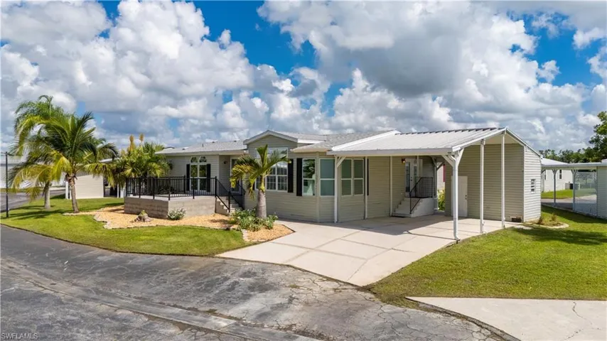 Ranch-style home featuring a front yard, an attached carport, driveway, and a patio