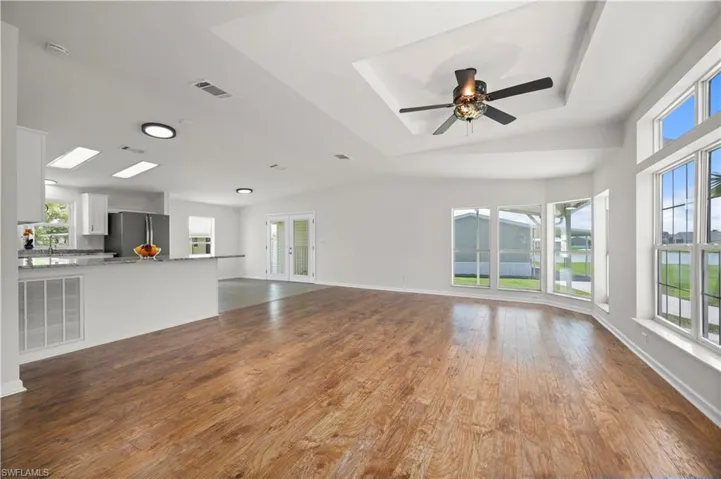 Unfurnished living room with dark wood-style floors, french doors, and a ceiling fan