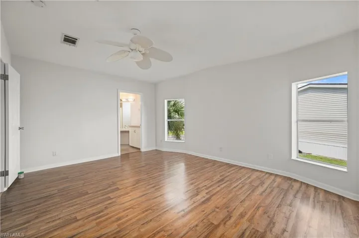 Unfurnished bedroom featuring wood finished floors, a ceiling fan, and connected bathroom