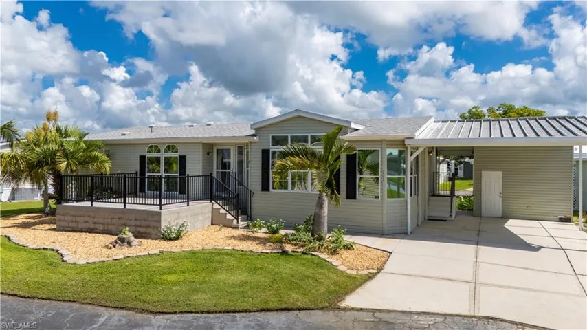 View of front facade with a carport, a front yard, concrete driveway, roof with shingles, and a patio area