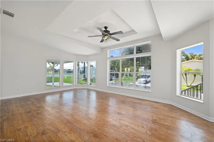 Unfurnished living room featuring a tray ceiling, hardwood / wood-style flooring, and a ceiling fan