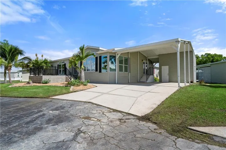 View of front of property with driveway, a front lawn, and a carport