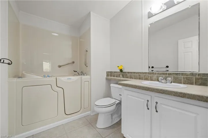 Bathroom featuring light tile patterned floors, vanity, shower / tub combination, backsplash, and ornamental molding