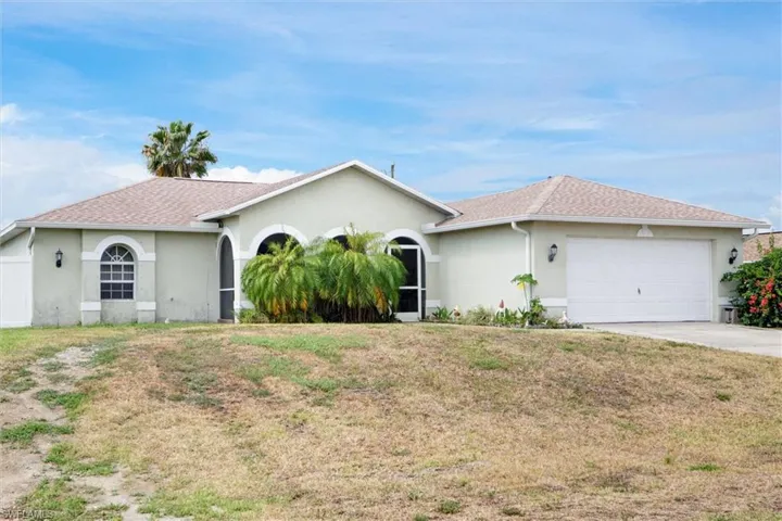 Charming single-story stucco home featuring a two-car garage, elegant arched entryways, and manicured curb appeal