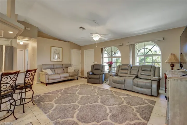 Sun-filled living room featuring vaulted ceilings, arched windows that flood the space with natural light, and tile flooring throughout