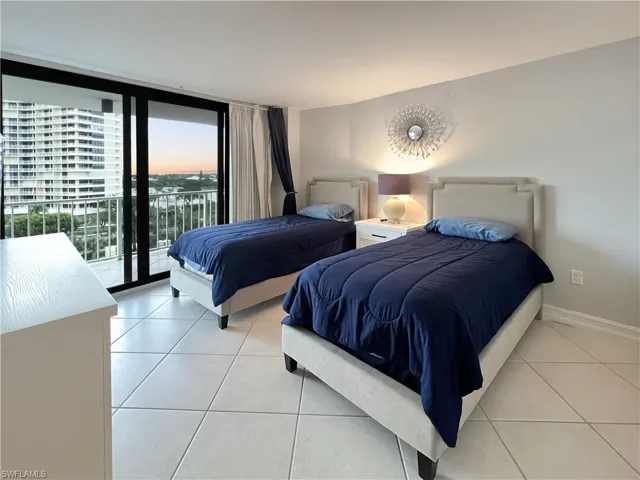 Bedroom with light tile patterned floors, floor to ceiling windows, and access to exterior