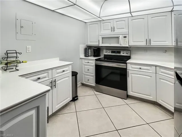 Kitchen featuring appliances with stainless steel finishes, light countertops, white cabinetry, and electric panel
