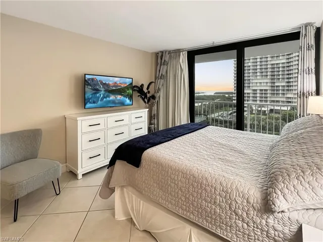 Bedroom with light tile patterned flooring, access to exterior, and a wall of windows