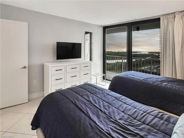 Bedroom featuring light tile patterned floors, access to outside, and expansive windows