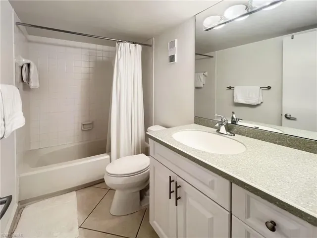 Full bathroom featuring shower / bath combination with curtain, light tile patterned floors, and vanity