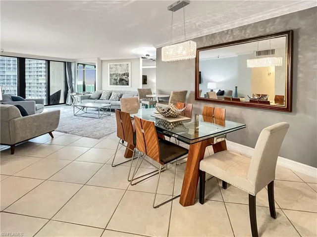 Dining area with a wall of windows, light tile patterned flooring, a chandelier, and crown molding
