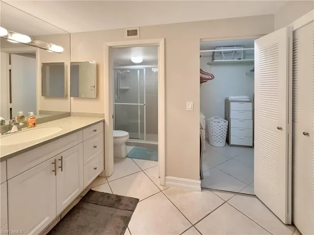 Bathroom featuring vanity, a stall shower, light tile patterned floors, and a spacious closet