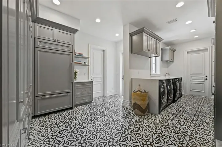 Kitchen with gray cabinetry, paneled built in fridge, recessed lighting, washing machine and dryer, and open shelves