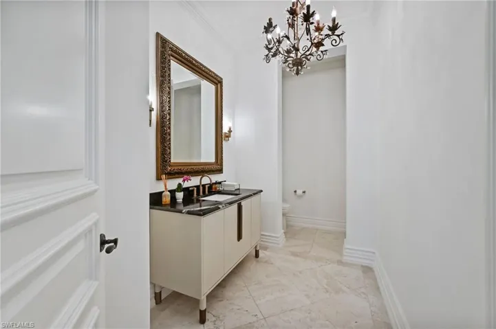 Bathroom featuring ornamental molding, a chandelier, vanity, and light tile patterned flooring
