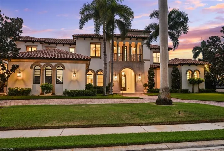 Mediterranean / spanish-style home featuring a balcony, stucco siding, a lawn, curved driveway, and a tile roof