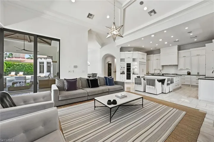 Living room featuring crown molding, arched walkways, recessed lighting, and a high ceiling