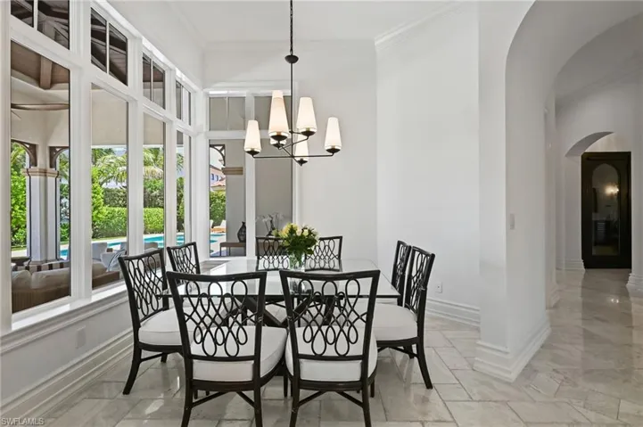 Dining room with arched walkways, ornamental molding, and a chandelier