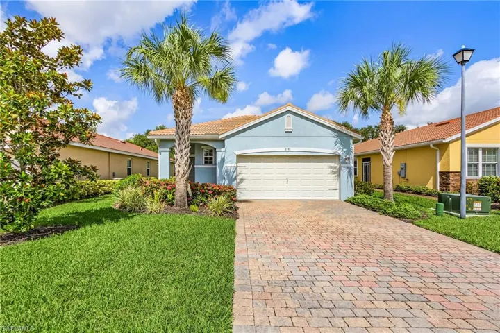 View of front facade featuring an attached garage, decorative driveway, a front yard, stucco siding, and a tiled roof