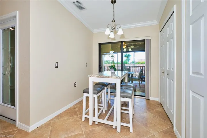 Dining room with ornamental molding, a chandelier, and light tile patterned floors