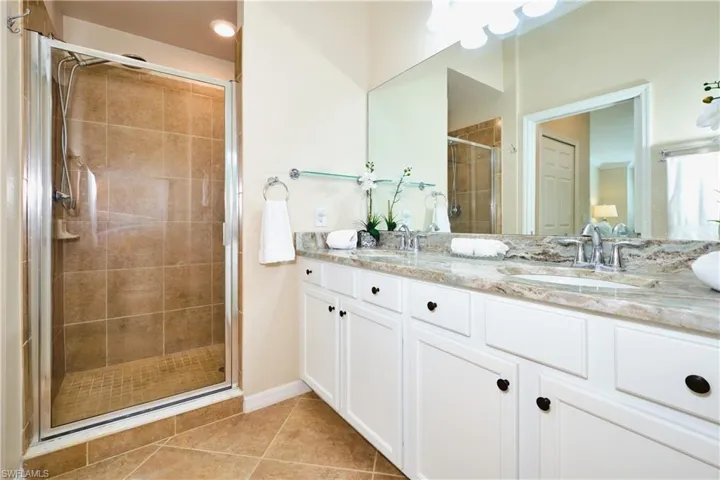 Full bathroom featuring double vanity, a stall shower, and tile patterned floors