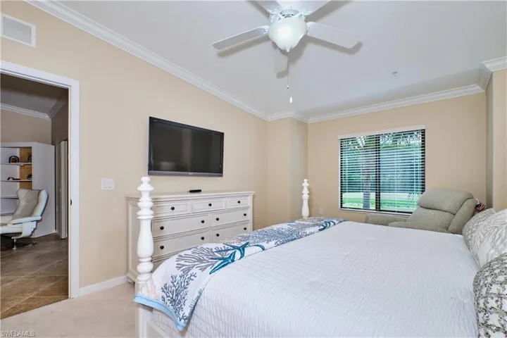 Carpeted bedroom featuring crown molding and ceiling fan